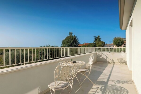 A balcony with white metal chairs and a table, a white railing, and a clear blue sky. - Stylish villa for 8 people in Tar-Vabriga (Tar-Vabriga)