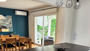 Uma cozinha moderna com uma ilha central, uma área de refeições com cadeiras de madeira e vista para um pátio exterior através de portas de vidro.