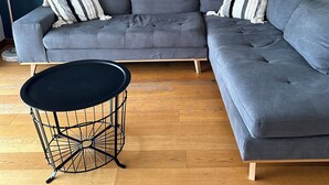 Uma sala de estar moderna com um sofá modular cinza, uma mesa de centro redonda preta e espelhos decorativos na parede.
