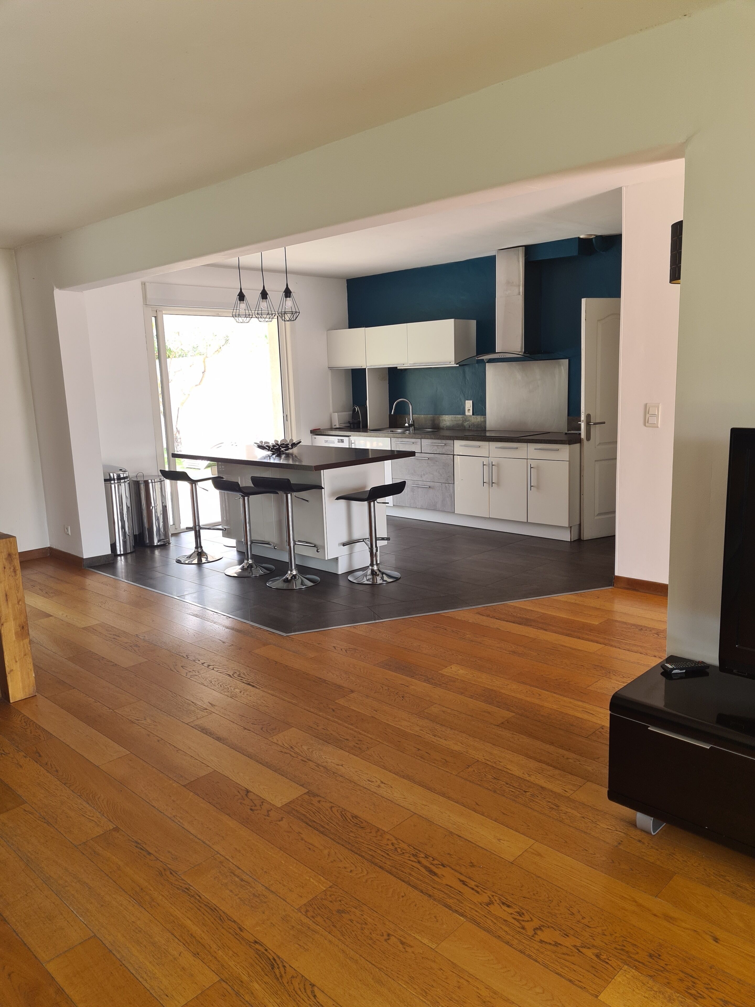 Une cuisine moderne avec des meubles blancs, un coin repas comprenant une table et des chaises, et un plancher en bois.