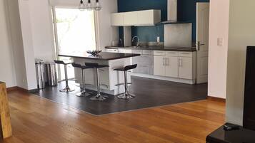 Une cuisine moderne avec des meubles blancs, un coin repas comprenant une table et des chaises, et un plancher en bois.