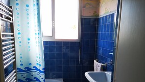 Une salle de bain avec une baignoire, un lavabo et une fenêtre.
