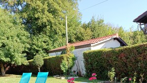 Un jardin avec une table et des chaises blanches, entouré d’herbe verte et d’arbres.