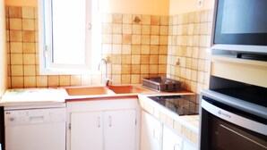 Une cuisine avec des meubles blancs, un lave-vaisselle, une cuisinière et un four à micro-ondes.
