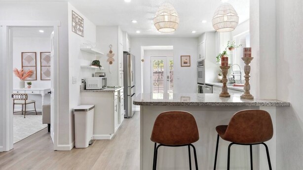 A modern kitchen with a central island, stainless steel appliances, and pendant lighting. - Modern Family Home | Rooftop Patio | Game Room (Denver)