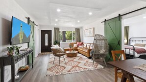 A spacious living area with a sofa set, a dining table, and a television mounted on the wall. - Modern Family Home | Rooftop Patio | Game Room (Denver)