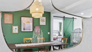 A dining area with a table, chairs, a woven pendant light, framed artwork, and a green wall. - Modern Family Home | Rooftop Patio | Game Room (Denver)