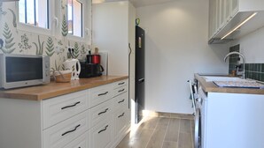A kitchen with white cabinets, a microwave, a kettle, and a refrigerator. - Charming cottage in Saint Remy de Provence, 4-5 people with pool and garden (France)