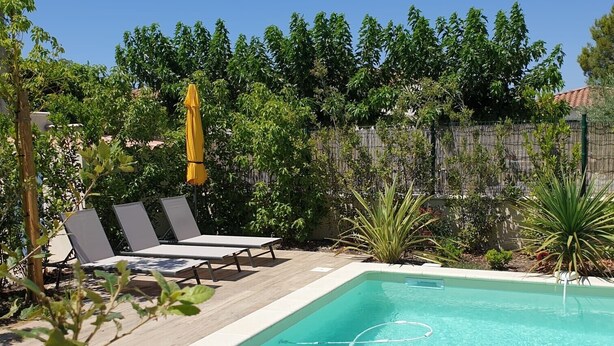 A rectangular swimming pool with clear blue water, surrounded by a wooden deck. There are lounge chairs and a yellow umbrella. - Charming cottage in Saint Remy de Provence, 4-5 people with pool and garden (France)