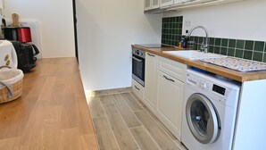 A compact kitchen with a washing machine, a sink, and a small oven. - Charming cottage in Saint Remy de Provence, 4-5 people with pool and garden (France)