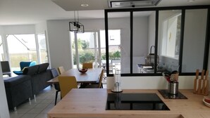 Una cocina moderna con encimera de madera, un lavabo y una zona de comedor con mesa y sillas.
