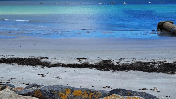 Una playa con rocas grandes y una vista despejada del mar.