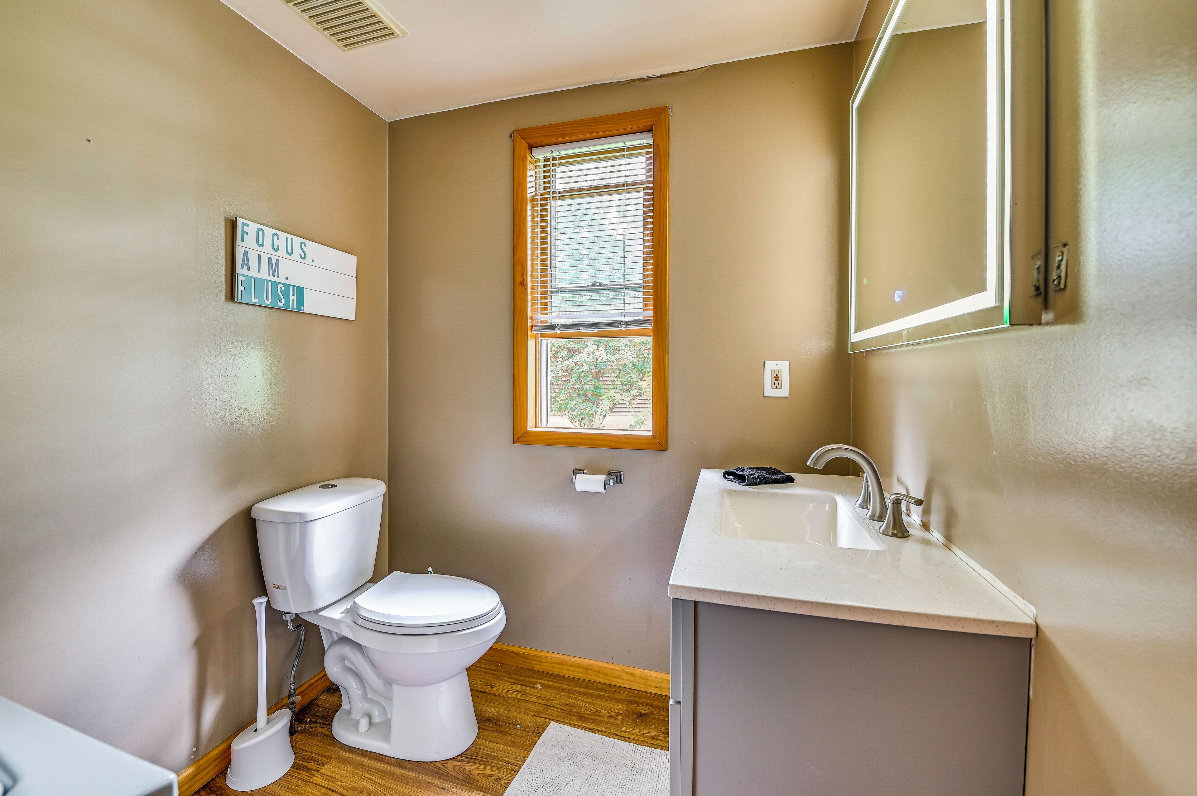 A small bathroom with a toilet, sink, and window.