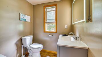 A small bathroom with a toilet, sink, and window.