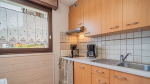 Eine kleine Küche mit Holzausstattung, einem Edelstahl-Spülbecken und einer Kaffeemaschine.