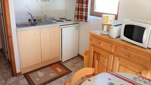 Une cuisine compacte équipée d’un micro-ondes, d’un grille-pain et d’une bouilloire sur le plan de travail, d’un petit réfrigérateur et d’un évier avec un égouttoir à vaisselle.