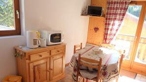 Une petite cuisine avec un meuble en bois, un four à micro-ondes, un grille-pain et une table avec des chaises.