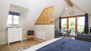 Ein Schlafzimmer mit Bett, Kommode, Stuhl und einem Essbereich mit Tisch und Stühlen.