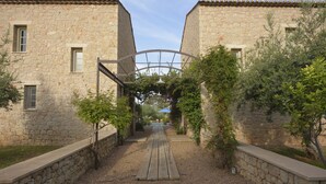 A stone building with a wooden pathway leading to a covered area. - Liodentra (West Mani)