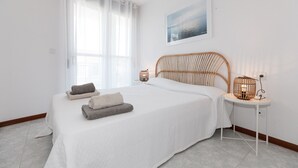 A bedroom with a bed, a bedside table with a lamp, and a window with curtains. - Beachfront Apartment - Peace and Beach - UHC RIVIERA (Miami Playa)