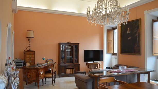 Ein Wohnzimmer mit einer Chandelier, einem Fernseher und einem Essbereich mit Tisch und Stühlen.