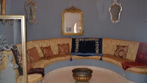 Ein Zimmer mit einer gebogenen, goldenen Couch, einem zentralen Spiegel und zwei Wandspiegeln.
