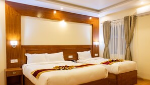 A hotel room with a large bed, two bedside tables, a wooden headboard, and a window with curtains.