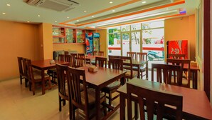A restaurant with wooden tables and chairs, a Pepsi vending machine, and a large window with a view of the outside.