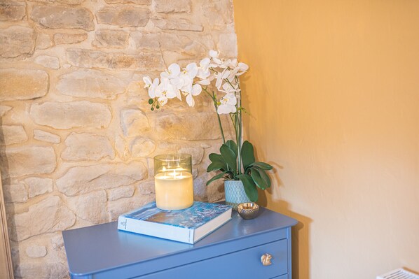 A blue nightstand with a lit candle, a book, and a potted plant with white flowers. - Cosy Dog Welcoming, Countryside Retreat (Lancaster)