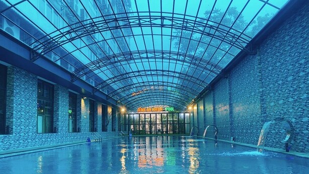 A large indoor swimming pool with a glass ceiling and stone walls. - Binh An Nhien Hotel (Hoa Lu)