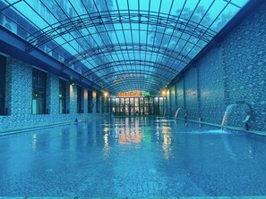 A large indoor swimming pool with a glass ceiling and stone walls. - Binh An Nhien Hotel (Hoa Lu)