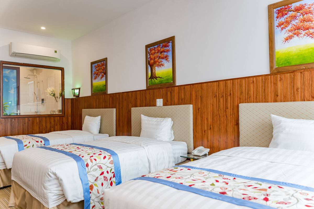 Una habitación de hotel con dos camas, paneles de madera y tres cuadros en la pared.