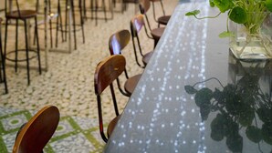 An outdoor dining area with tables and chairs, string lights overhead, and a green umbrella providing shade. - Binh An Nhien Hotel (Hoa Lu)