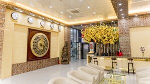 A hotel lobby with a reception desk, seating area, clocks, and a decorative wall. - Binh An Nhien Hotel (Hoa Lu)