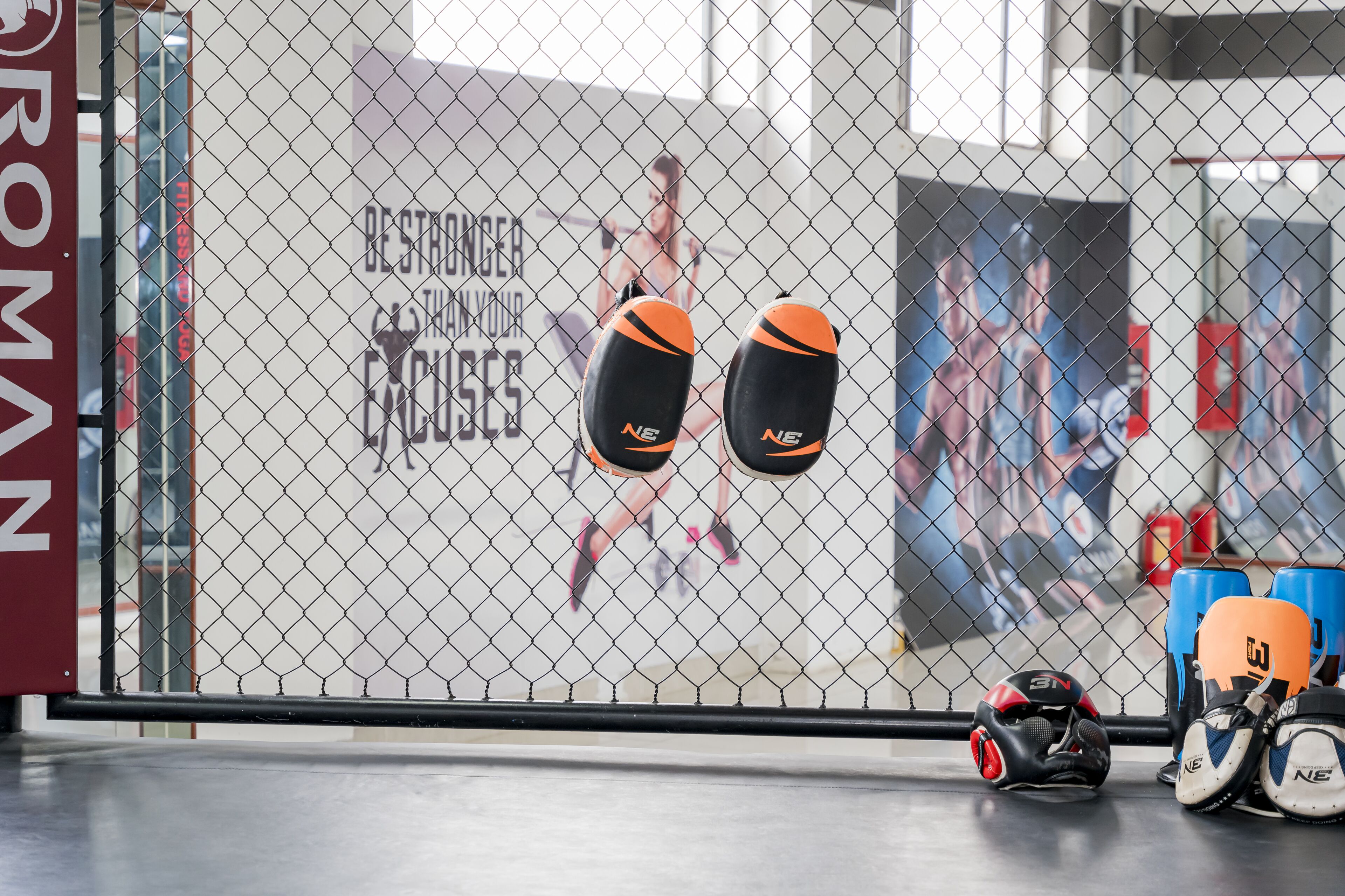 A gym with boxing equipment, including pads and gloves, and a motivational poster on the wall.