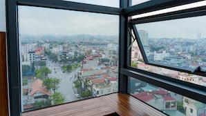 A view from a high-rise window overlooking a cityscape with buildings and roads. - Binh An Nhien Hotel (Hoa Lu)