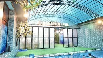 Una piscina interior con techo de cristal, un letrero que dice "BINH AN NHIEN POOL" y una silla de salvavidas.