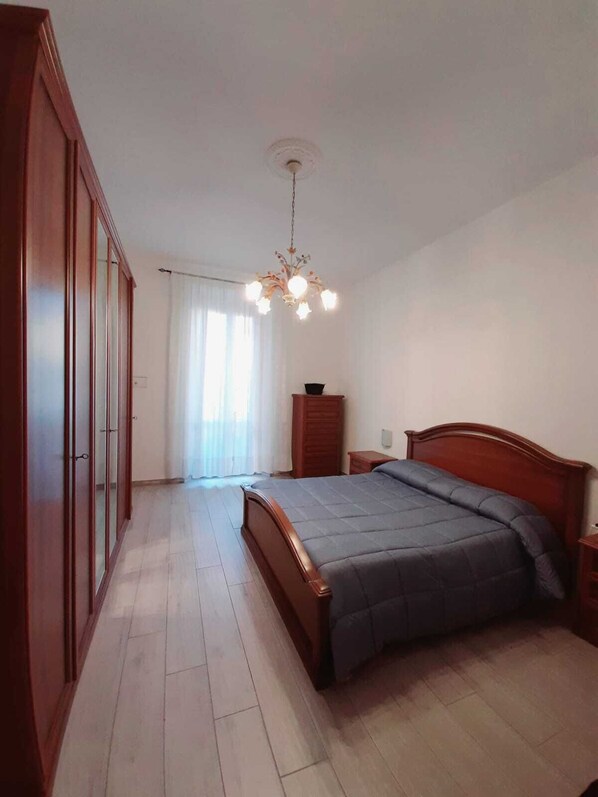 Une chambre à coucher avec un lit en bois, une table de chevet, une armoire et un lustre.