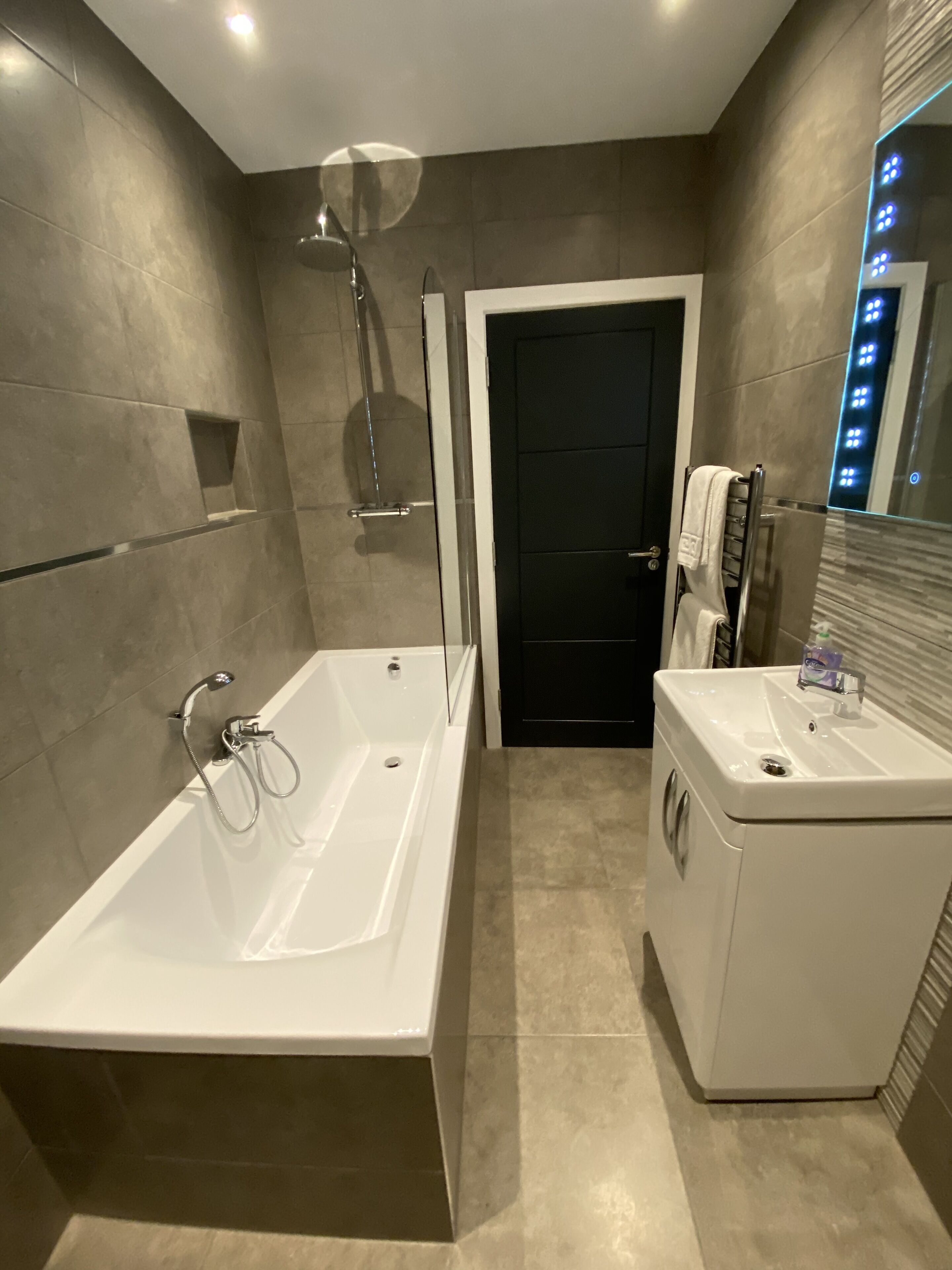 A modern bathroom with a large bathtub, a separate sink, and a shower area.