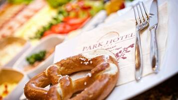 Una mesa de desayuno con un pretzel, un tenedor y una servilleta con la inscripción 'PARK HOTEL'.