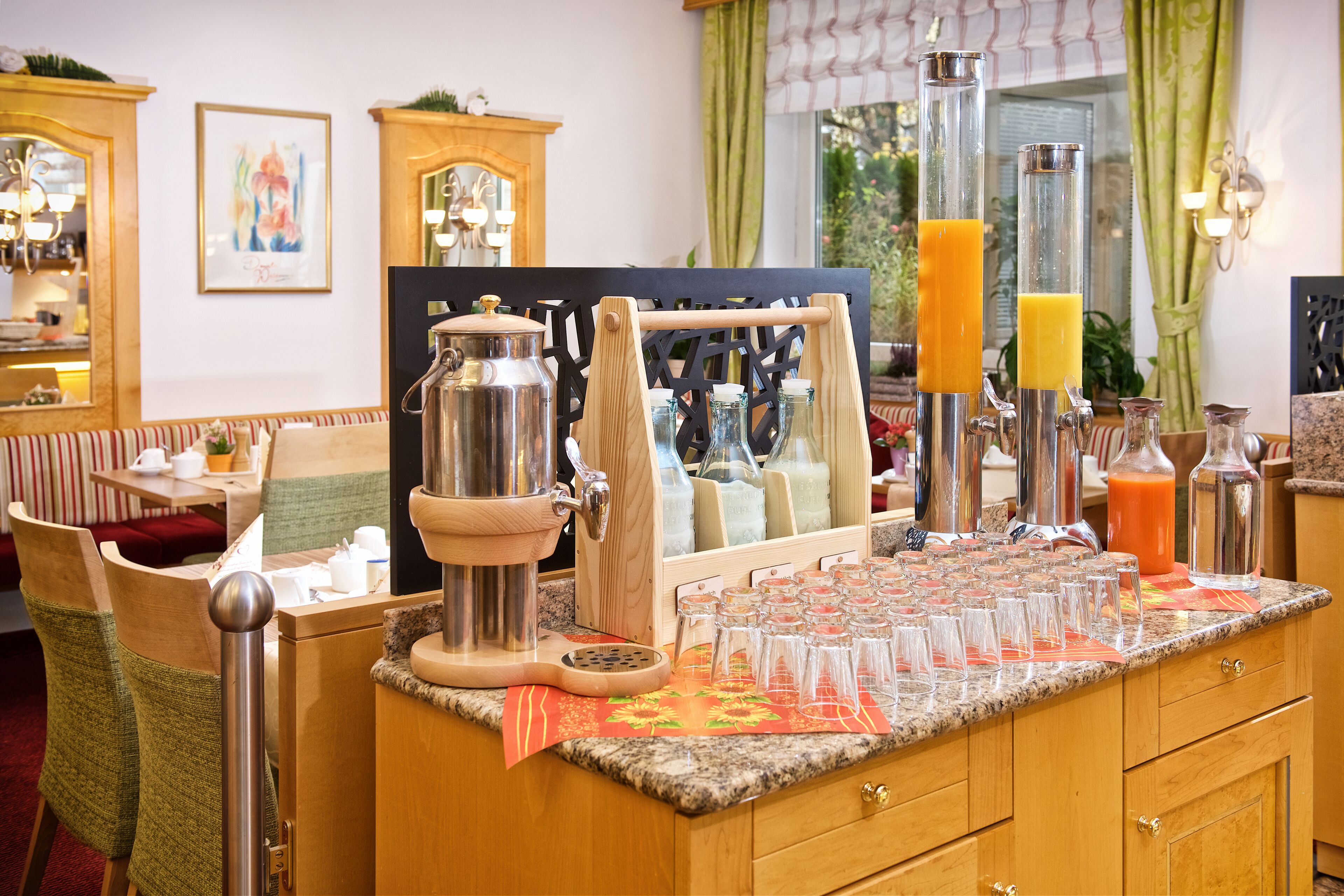 Ein Frühstücksbuffet mit einer Kaffeemaschine, Saftspendern und verschiedenen Gläsern.