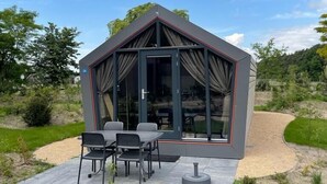 Een moderne, glazen structuur met een eetgedeelte met een tafel en stoelen.