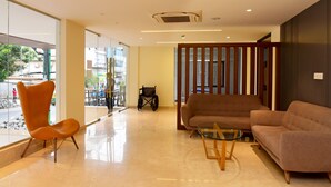 Un vestíbulo moderno con separador de vidrio, una silla de ruedas y zonas de estar.