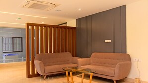 Una sala moderna con dos sofás, una mesa de centro de cristal y un separador de madera.