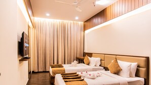 Habitación de hotel con dos camas, televisor y ventilador de techo.