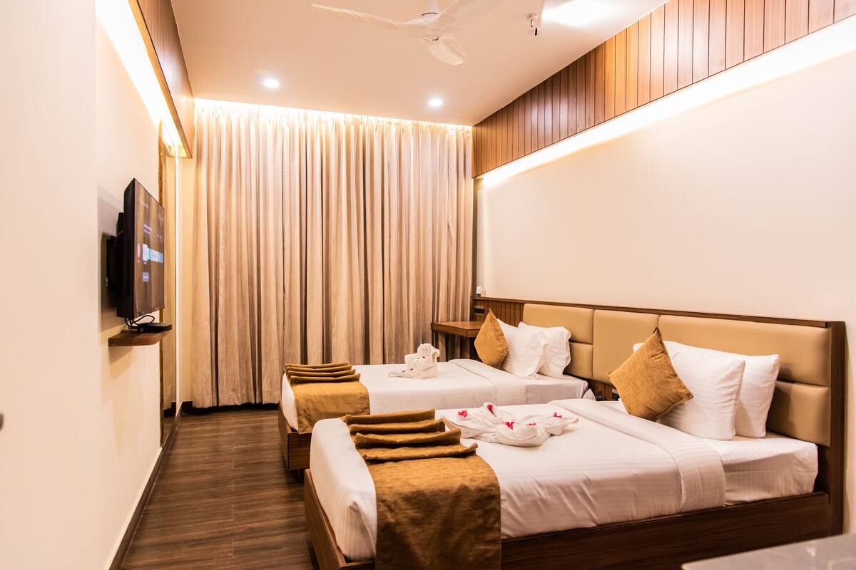 A hotel room with two beds, a TV, and a ceiling fan.