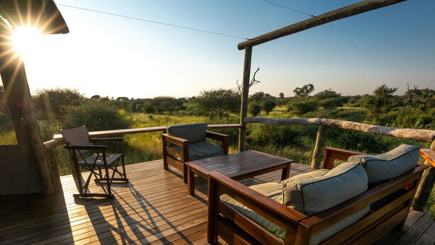 A wooden deck with a sofa and chairs, overlooking a grassy landscape. - Omogolo Hideaways - Mangwane Oratile · A35,Tsau, North-West District, BW (Tsau)