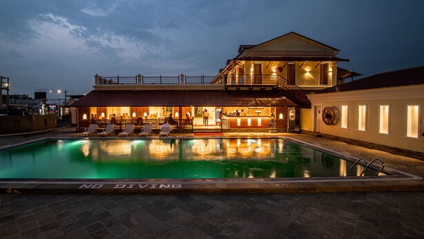 A swimming pool with a bar area and a building with a balcony. - Manigram Bishram Batika Pvt Ltd (Tilottama)