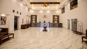 A spacious lobby with marble flooring, a central reception desk, and a chandelier. - Manigram Bishram Batika Pvt Ltd (Tilottama)