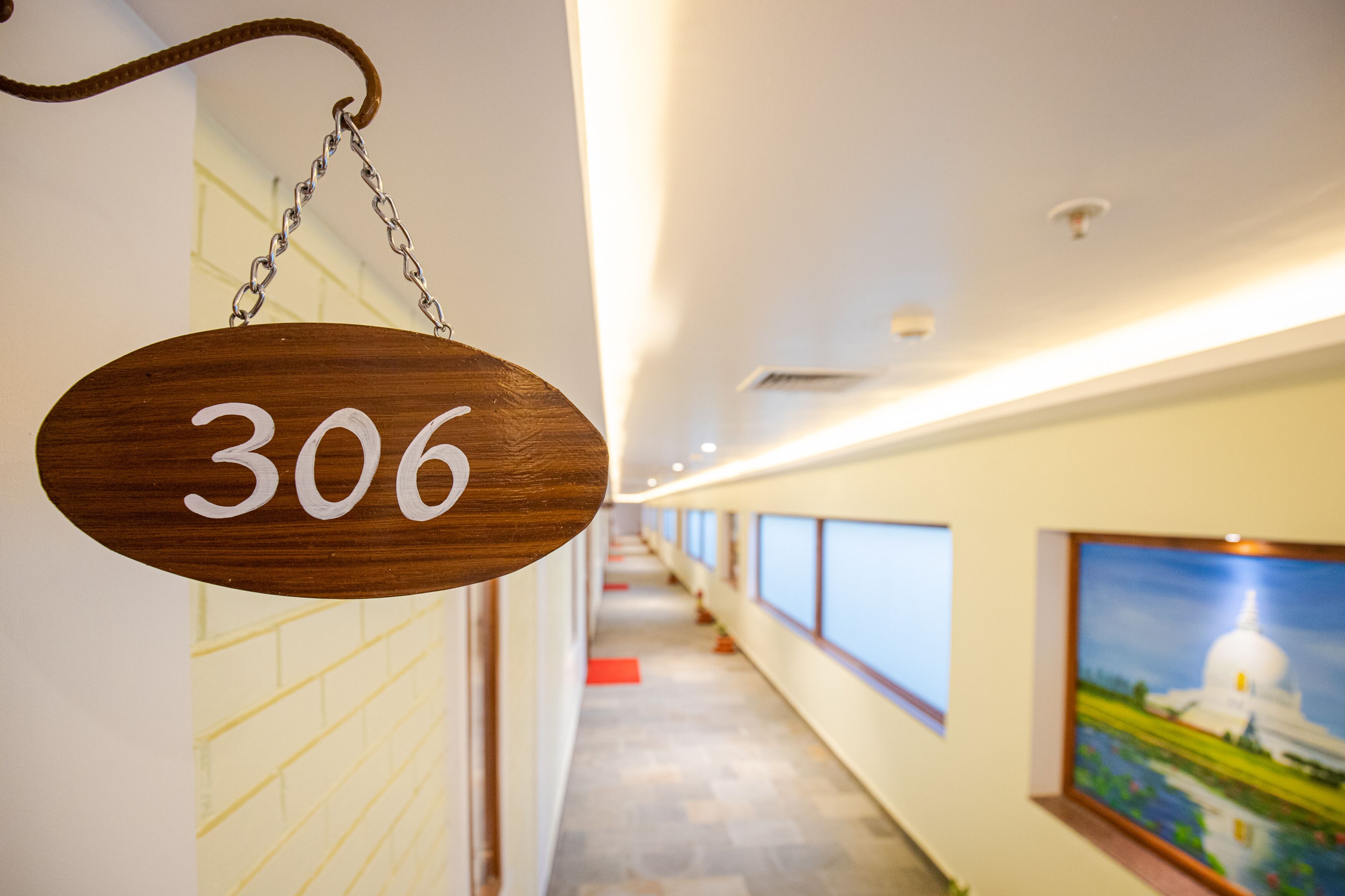 A corridor with a wooden sign hanging from the ceiling indicating room number 306.